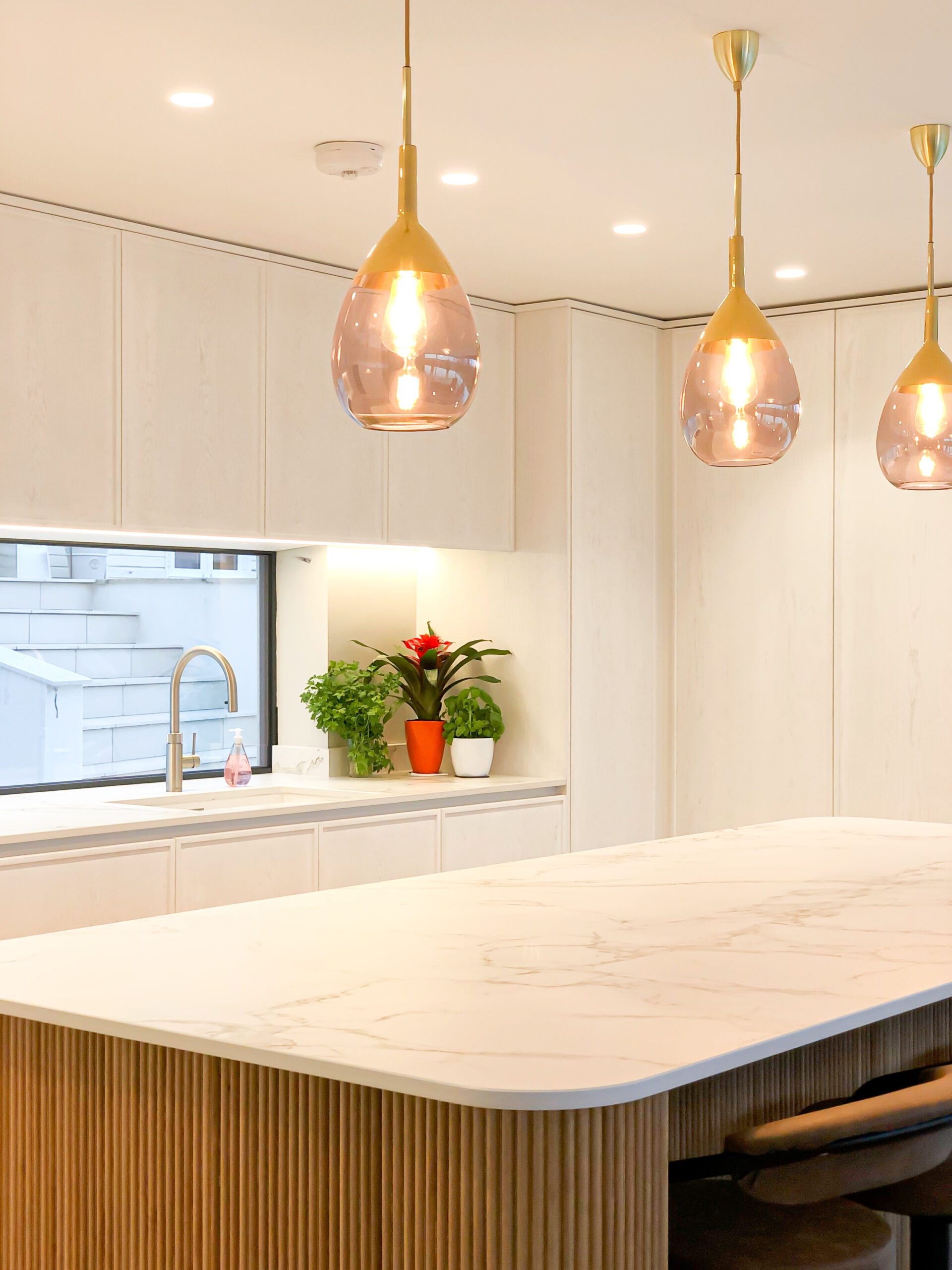 Clean white stone island and worktops in a modern kitchen