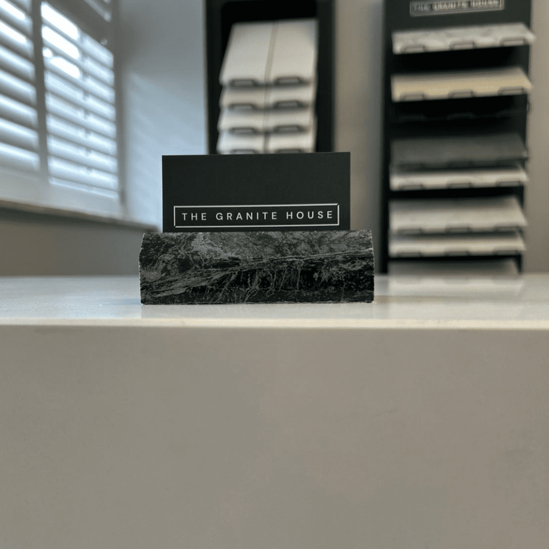 The Granite House business card displayed on a stone sample inside the Bicester showroom, showcasing local craftsmanship and personal service.